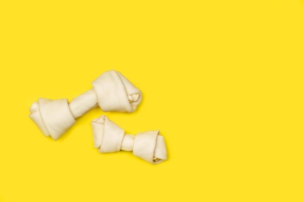 Rawhide bones on a yellow background with copy space