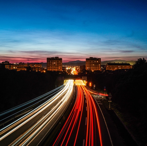 Лучи света в замедленной съемке автомобилей, едущих по шоссе ночью, чтобы въехать и выехать из города