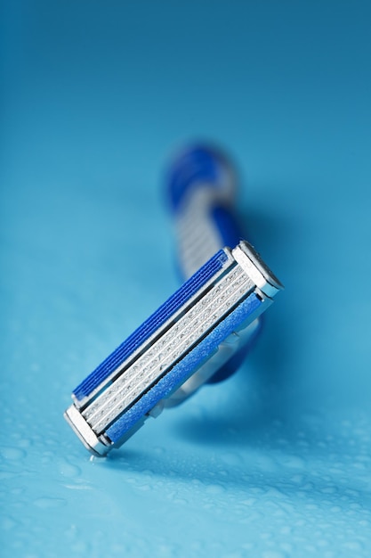 Razor blades on a blue background with drops of icy water