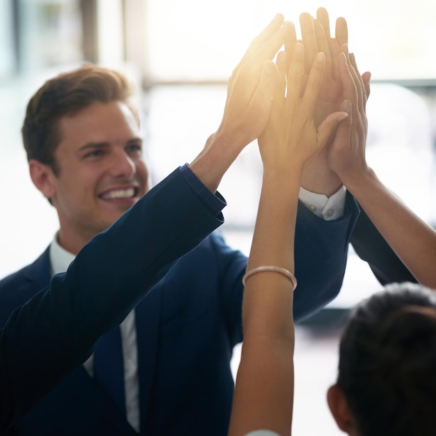 Reaching for their greatest goals together Cropped shot of a group of businesspeople high fiving together in an office