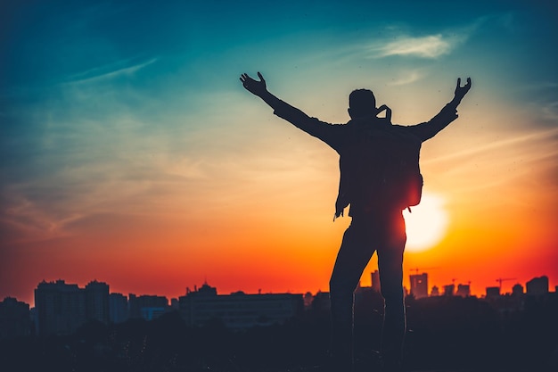 明るい空の夕日に対してバックパックを持った男のトップサクセスコンセプトのシルエットに到達