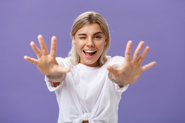 Reaching to you. portrait of flirty good-looking and confident stylish woman winking playfully and smiling pulling hands towards