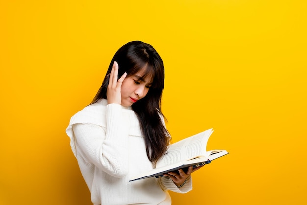 Read a book study with the protagonist seek knowledge food for thought girl reading a book and smiling in the photo studio yellow backdrop