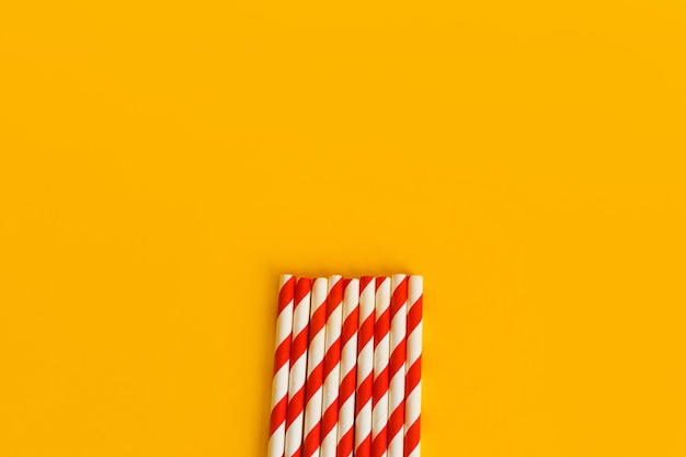 Read white striped paper straws on yellow background Ecofriendly concept