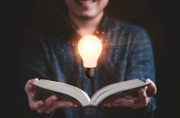 Photo 教育、知識、創造的な思考のアイデアの概念を読むためのフローティング白熱電球を備えたリーダーオープンブック。
