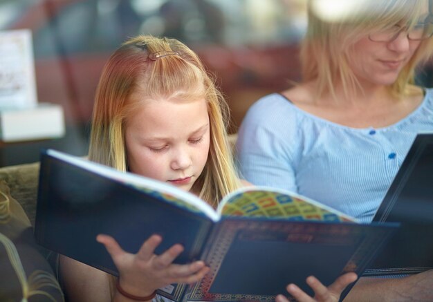 독서는 두뇌 운동을 한다 책을 읽는 동안 엄마 옆에 앉아 있는 귀여운 소녀