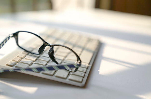 Reading glasses on keyboard next to windows