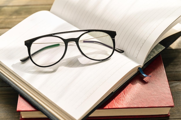 Reading glasses put on open book over wooden table