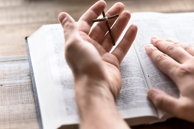 Чтение Библии с деревянным крестом в руке