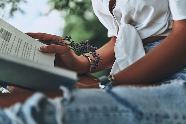 Photo reading interesting book. close-up of young woman holding an open book while spending time outdoors