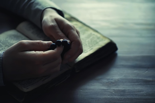 Чтение религиозной литературы Мужчина изучает Коран и разбирает четки