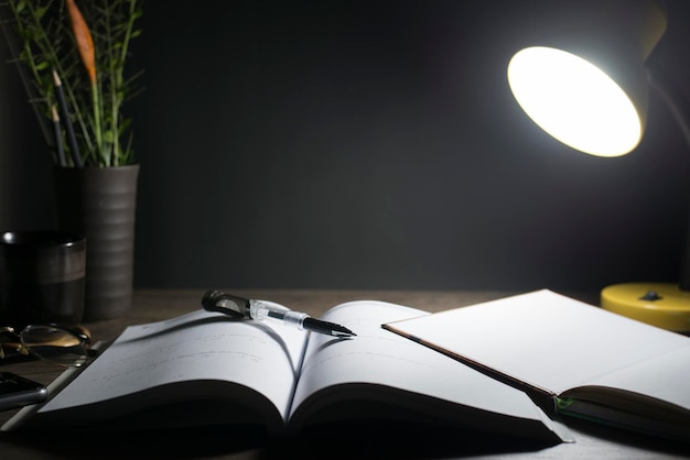 Reading table at night Open books on the table Closeup the pen tip Copyspace