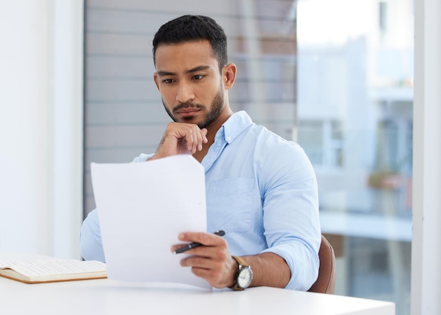 Reading through a new contract Shot of a young businessman going through paperwork in an office