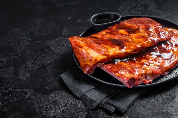 Ready for BBQ raw pork spare ribs with barbecue sauce Black background Top view Copy space