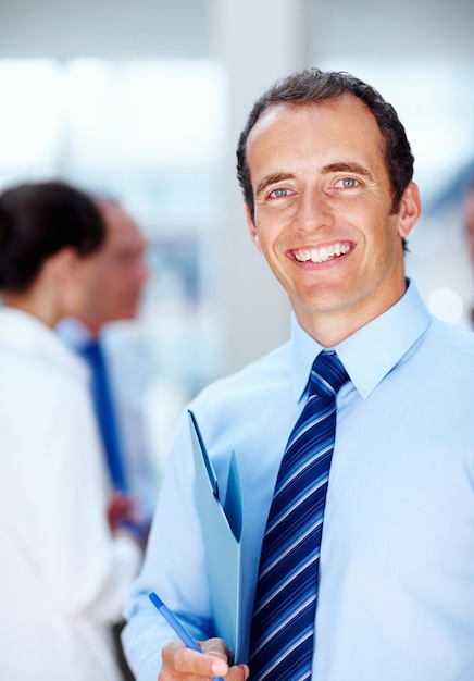 Photo ready to do business executive holding pen with colleagues in background