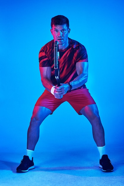 Ready to conquer the court Blue filtered shot of a man posing with a tennis racket in the studio