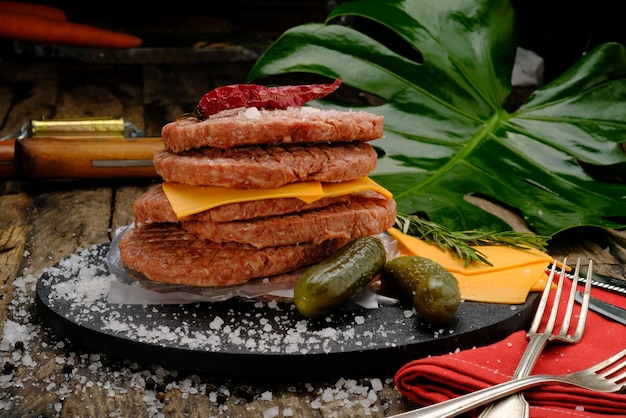 Ready-to-cook meatballs on a black plate on a wooden table, with cheddar cheese, salt and spices