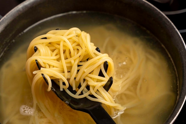 Ready cooked spaghetti is taken out of boiling water