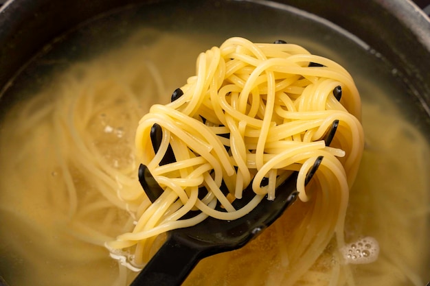 Ready cooked spaghetti is taken out of boiling water