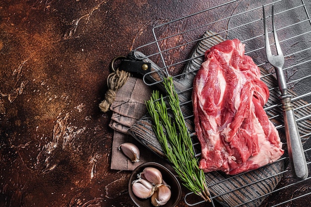 Ready for cooking on grill boneless lamb meat raw neck meat\
with herbs dark background top view copy space