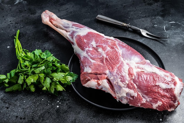 Photo ready for cooking raw lamb mutton leg with thigh black background top view