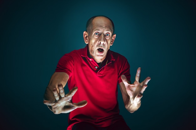 Ready to defend. portrait of crazy scared and shocked caucasian\
man isolated on dark background. copyspace for ad. bright facial\
expression, human emotions concept. watching horror on tv,\
cinema.