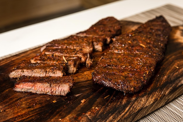 Ready to eat cooked grilled sliced piece of denver steak meat on wooden cutting board closeup