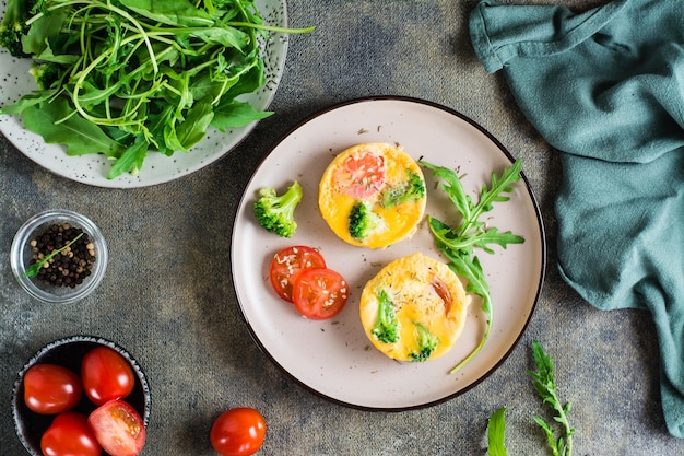 Ready to eat egg broccoli and tomato frittata on a plate on the table Homemade breakfast Top view