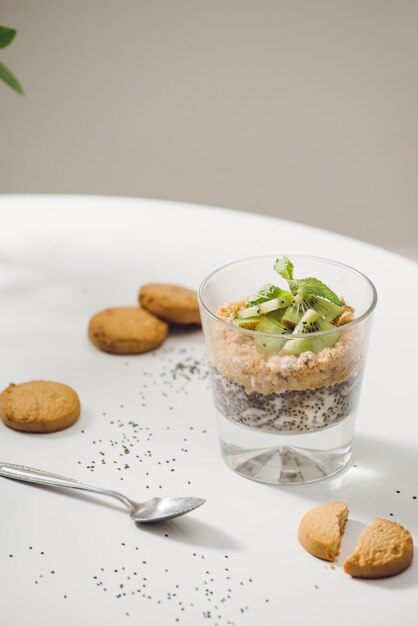 Pronto da mangiare sano e nutriente colazione - muesli con mandorle, semi di chia, banana e kiwi e bacche e un barattolo con latte nelle vicinanze