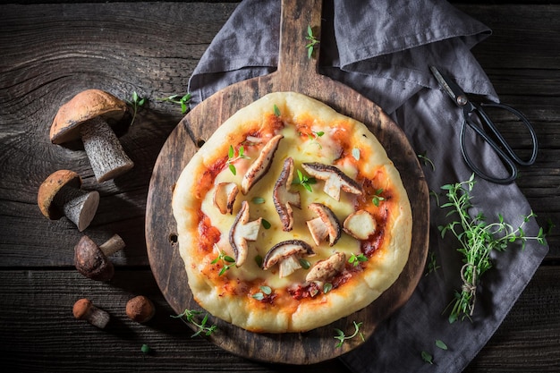 Ready to eat rustic pizza with noble mushrooms and thyme