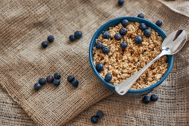 Ready to eat. Top view of healthy and useful breakfast cereals with blueberries, oats in bowl on isolated. Healthy snack or breakfast in the morning. Metal spoon in muesli