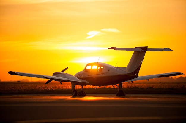 飛行する準備ができました。夕日を背景に空港で飛行機のトリミング画像