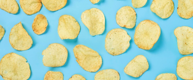 Ready fresh potato chips on a blue background Top view flat lay Banner