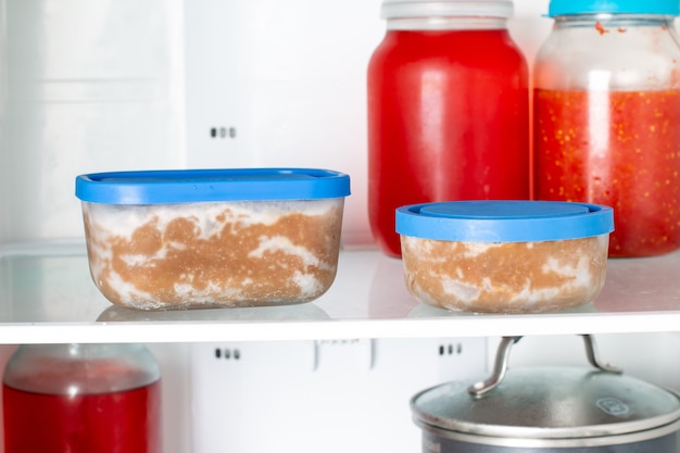 Ready frozen food in containers on the refrigerator shelf. Ready meal