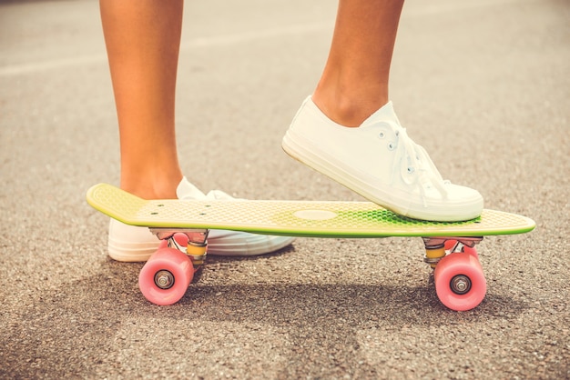 Ready to go. Close-up of woman holding her legs on skateboard