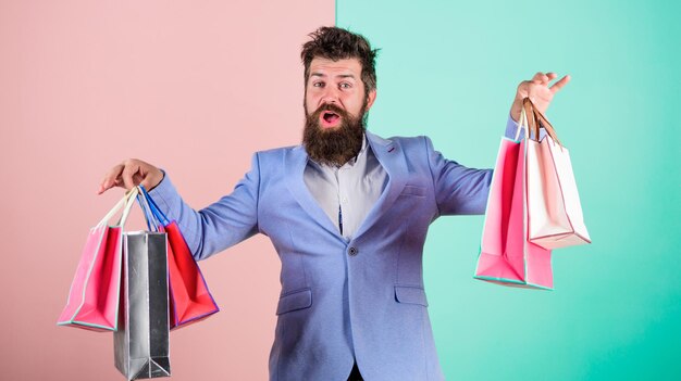 Ready for holiday Buy gifts in advance Enjoy shopping black friday Hipster shopping with discount Man bearded hipster businessman formal suit carry paper shopping bags Buy gifts for everyone