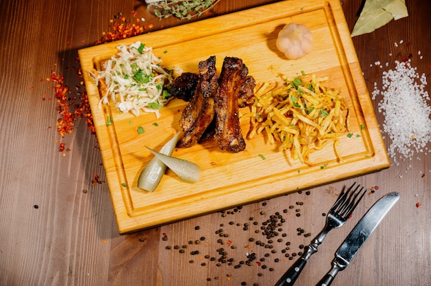 Ready-made dish of fried meat: lamb ribs with a side dish of potatoes. Serve on a wooden board.Top view