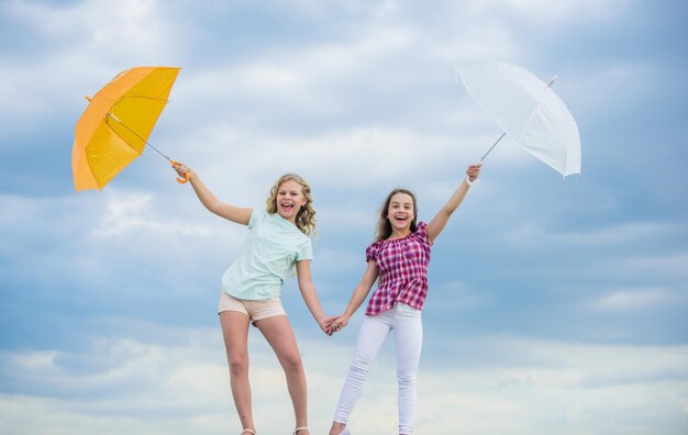 Ready for new adventures protected at autumn day happy small girls with umbrella positive and bright mood best friends school time autumn season rainy weather forecast fall kid fashion