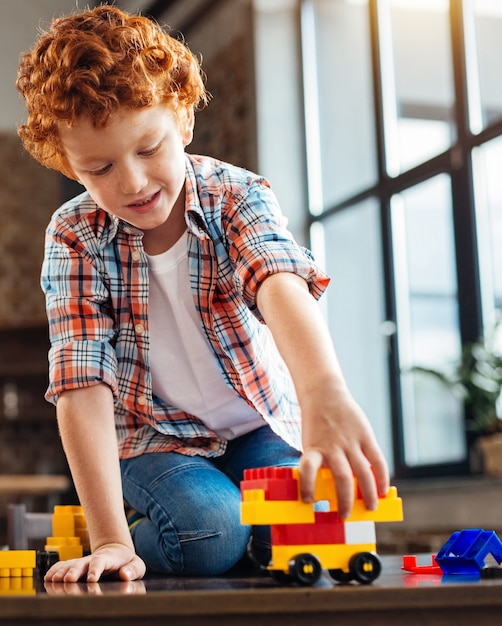 Ready steady go. Completely absorbed in the process of play redhead child focusing his attention a built plastic car