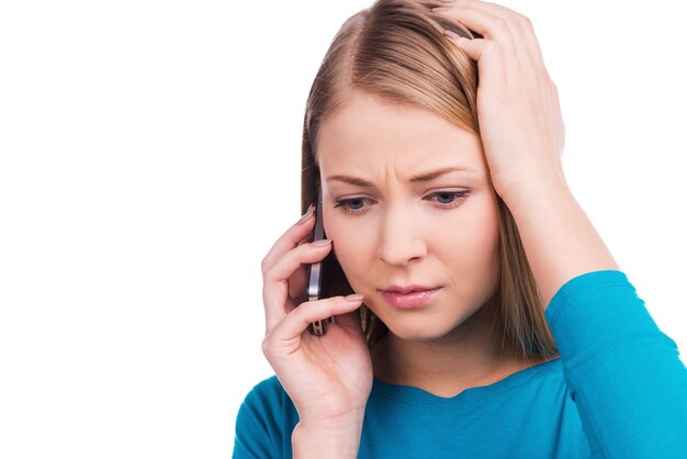 Not ready for this talk. Beautiful young women talking on the mobile phone and touching her head while standing against white background