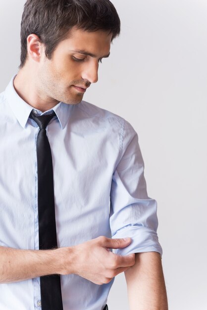 Ready to work. Confident young man in shirt and tie adjusting his sleeve