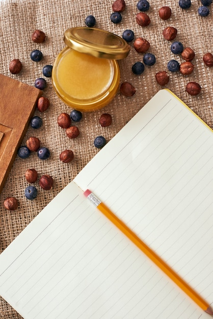 Готов написать рецепт. Карандаш и поваренная книга лежат на столе рядом с сушеными ягодами и медом