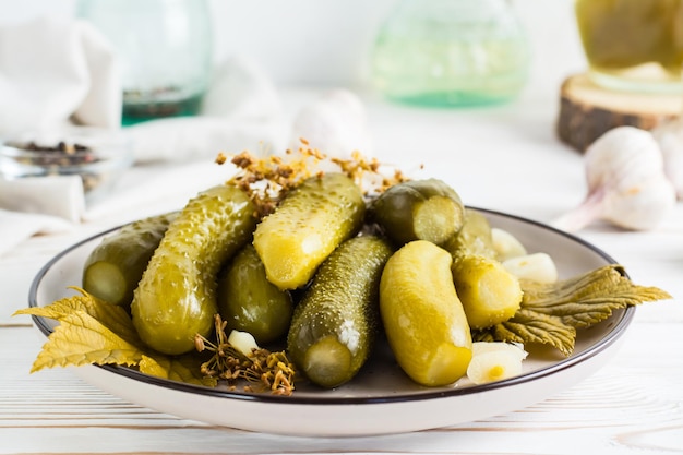 Readytoeat pickled cucumbers on a plate and ingredients for cooking on a wooden table Homemade snacks