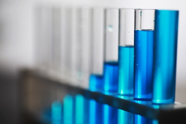 Reageerbuis met blauwe vloeistof op de laboratoriumtafel Onderzoek van vloeistof onder een microscoop
