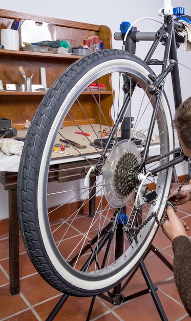 Real bicycle mechanic repairing black custom fixie bike in the workshop