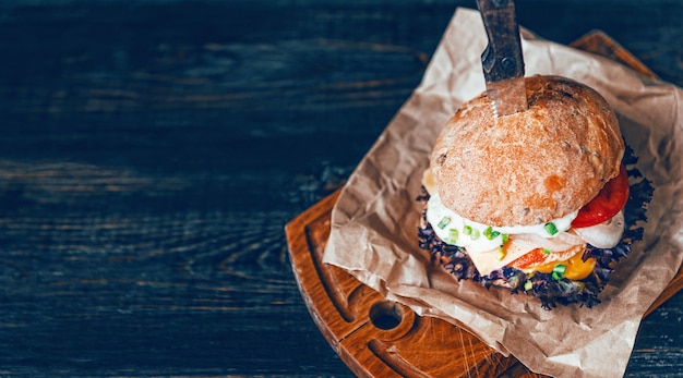 Un vero hamburger su uno sfondo di legno. con una grande e succosa cotoletta salsa tenera di formaggio e senape. rustico