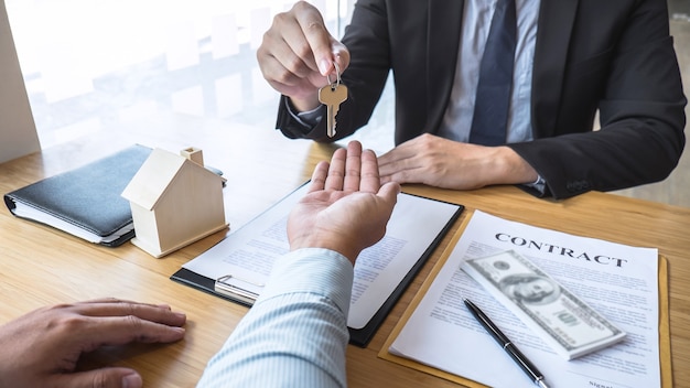 Real estate agent are presenting home loan and sending keys to customer after signing contract to buy house with approved property application form, Insurance Home concept.