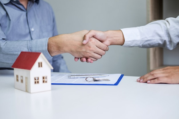 Real estate agent and customers shaking hands together celebrating finished contract 