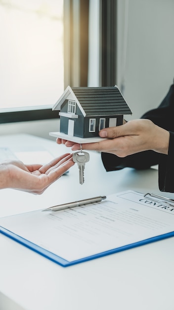 Photo a real estate agent gives a home model to the buyer woman.