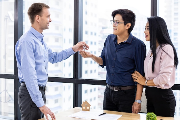 Real estate agent gives the house keys to the client after signing the real estate contract agreement.